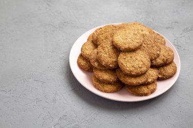 Gri bir yüzeyde pembe bir tabakta mısır gevreği kurabiyesi, yan görüş. Polis.