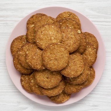 Beyaz ahşap bir yüzey üzerinde pembe bir tabakta mısır gevreği kurabiyesi.