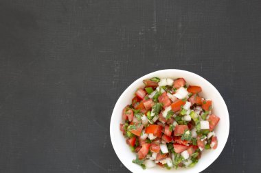 Pico de Gallo, siyah arka planda beyaz bir kasede, üst manzara. O