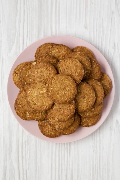 Beyaz ahşap arka planda pembe bir tabakta mısır gevreği kurabiyesi.