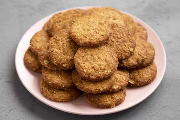 Cereal cookies on a pink plate on a concrete surface, side view.