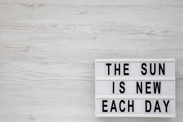 'Il sole è nuovo ogni giorno 'parole su una tavola moderna su un corteggiamento bianco — Foto Stock
