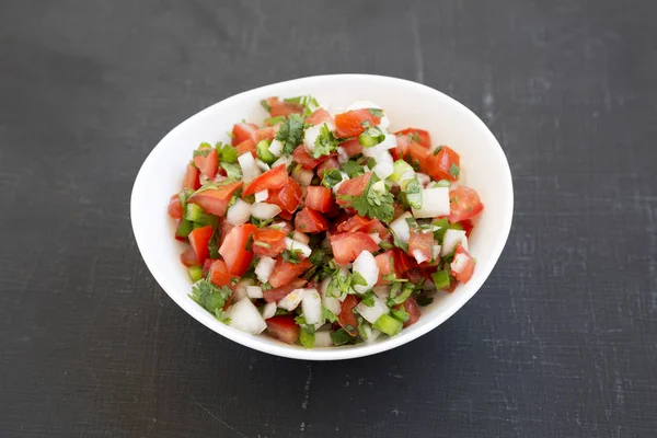 Pico de Gallo siyah arka planda beyaz bir kasede, yan görünüm. 
