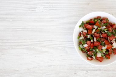Pico de Gallo beyaz bir kase içinde beyaz tahta bir yüzey üzerinde, üst yaşam