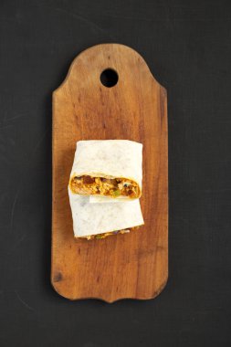 Siyah arka planda ev yapımı sucuklu kahvaltı dürümleri.