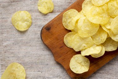 Kırsal tahta üzerinde tuz bulunan sarı patates cipsi.