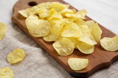 Kırsal ahşap bir tahtanın üzerinde tuzlu patates cipsi.