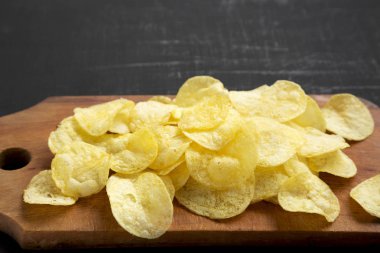 Kırsal ahşap bir tahtanın üzerinde tuzlu patates cipsi.