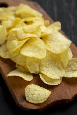 Kırsal ahşap bir tahtanın üzerinde tuzlu patates cipsi.