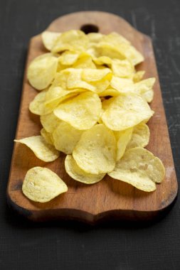 Kırsal ahşap bir tahtanın üzerinde tuzlu patates cipsi.