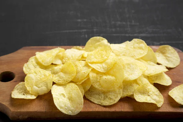 Kırsal ahşap bir tahtanın üzerinde tuzlu patates cipsi.