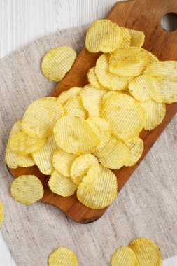 Tuzlu dalgalı patates cipsleri beyaz bir vu üzerinde ahşap bir tahta üzerinde