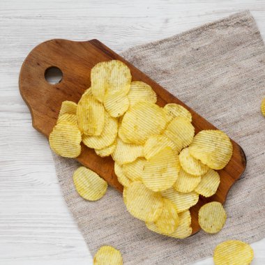 Tuzlu dalgalı patates cipsleri beyaz bir vu üzerinde ahşap bir tahta üzerinde