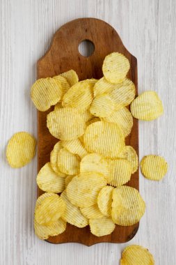 Tuzlu dalgalı patates cipsleri beyaz bir vu üzerinde ahşap bir tahta üzerinde