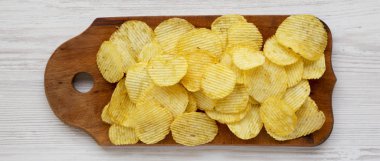 Tuzlu dalgalı patates cipsleri beyaz bir vu üzerinde ahşap bir tahta üzerinde