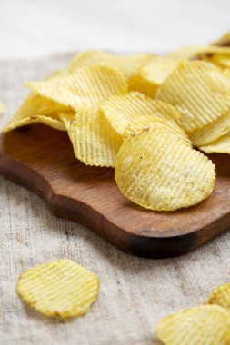 Köy tahtasında tuzlu dalgalı patates cipsi, düşük açılı hayat.