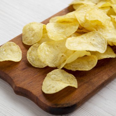 Kırsal ahşap bir tahtanın üzerinde tuzlu patates cipsi.