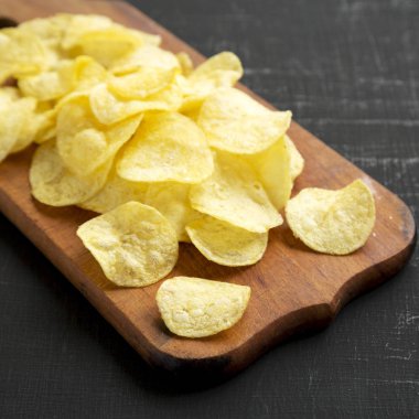Kırsal ahşap bir tahtanın üzerinde tuzlu patates cipsi.