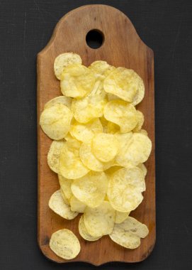 Kırsal ahşap bir tahtanın üzerinde tuzlu patates cipsi.