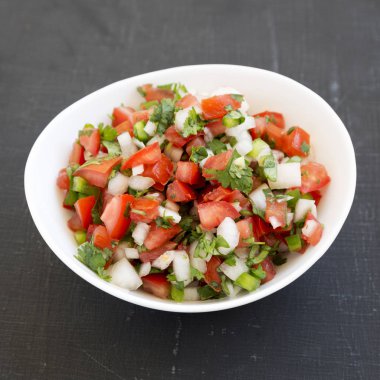 Pico de Gallo, siyah bir yüzey üzerinde beyaz bir kasede, alçak açılı bir manzara.