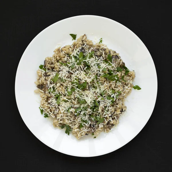 Homemade mushroom risotto on a white plate over black background — Stock Photo, Image