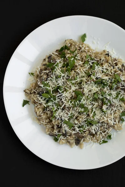 Homemade mushroom risotto on a white plate on a black surface, t — Stock Photo, Image