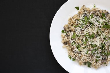 Siyah arka planda beyaz tabakta ev yapımı mantarlı risotto.