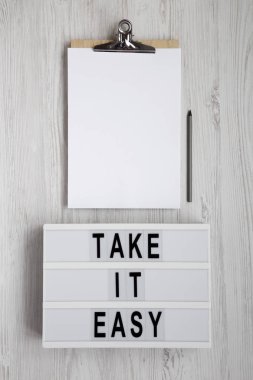 'Sakin ol' kelimeleri ışık kutusunda, boş sayfalı panoda.