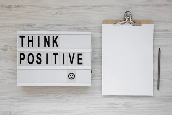 'Think positive' words on a lightbox, clipboard with blank sheet — Stock Photo, Image