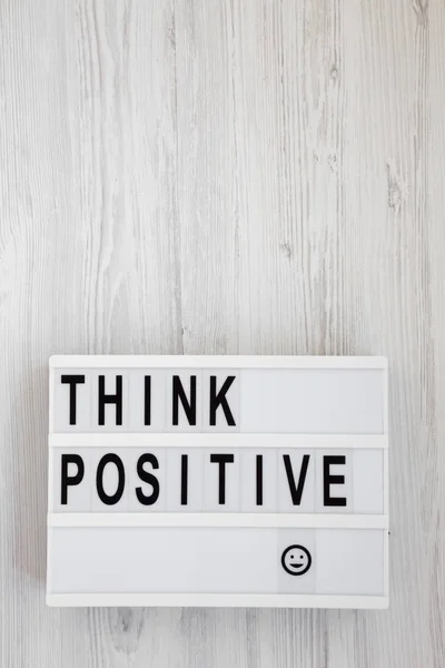 'Pense positivo' palavras em uma placa moderna em um backg de madeira branco — Fotografia de Stock
