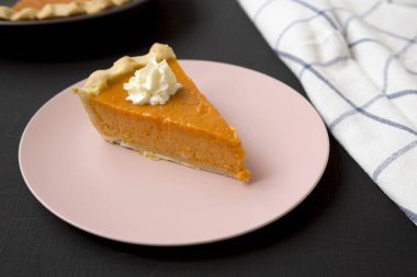 Ev yapımı Şükran Günü balkabağı turtası. Siyah bir torba üzerinde pembe bir tabakta.