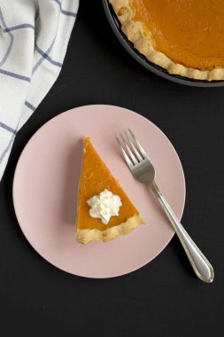 Ev yapımı Şükran Günü balkabağı turtası. Siyah bir torba üzerinde pembe bir tabakta.