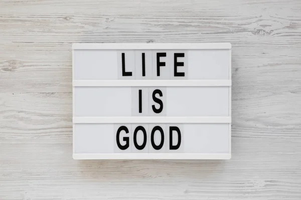 'La vida es buena' palabras en un tablero moderno sobre una superficie de madera blanca — Foto de Stock