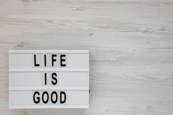'La vida es buena' palabras en un tablero moderno sobre un fondo de madera blanca — Foto de Stock
