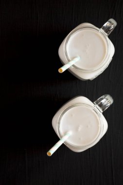 Siyah arka planda cam kavanozda hindistan cevizi sütü, üst manzara. Dümdüz, tepeden, yukarıdan. Metin için boşluk.