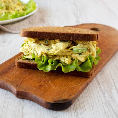 Beyaz ahşap bir yüzey üzerinde ahşap bir tahta üzerinde ev yapımı Tavuklu Sandviç. Yakın plan..