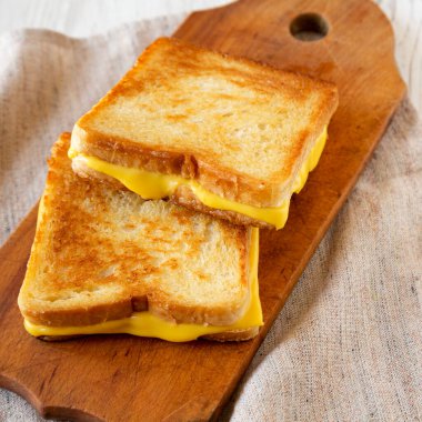 Ev yapımı ızgara peynirli sandviç, ahşap bir tahta üzerinde, düşük açılı..