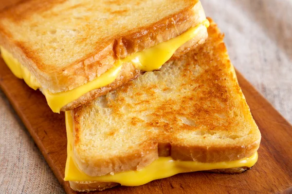 Ev yapımı ızgara peynirli sandviç, ahşap bir tahta üzerinde, alçak açılı. Yakın plan..