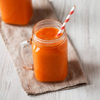 Beyaz ahşap arka planda Mango Havuç Smoothie dolu cam kavanozlar.. 