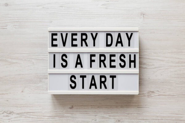'Every day is a fresh start' words on a lightbox on a white wooden surface, top view. Overhead, from above, flat lay. 