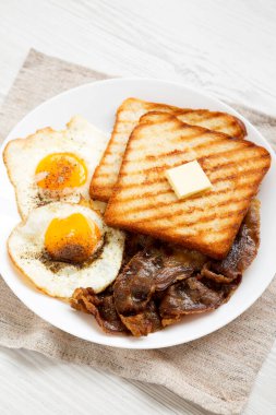 Beyaz ahşap bir yüzey üzerinde beyaz bir tabakta, düşük açılı ev yapımı sağlıklı yumurtalı kahvaltı. Yakın plan..