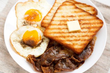 Beyaz ahşap arka planda beyaz bir tabakta ev yapımı sağlıklı Sunnyside Yumurta Kahvaltısı. Yakın plan..