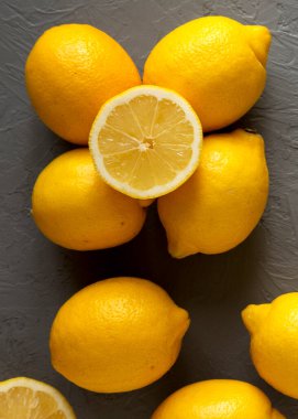 Gri arka planda taze, olgun, sarı organik limonlar, üst manzara. Dümdüz, tepeden, yukarıdan. 
