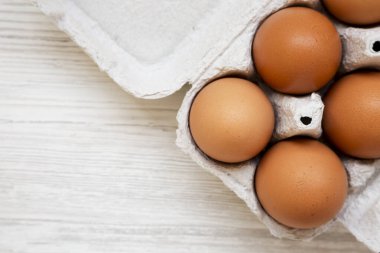 Kağıt bir kutuda çiğ kahverengi yumurta, üst manzara. Dümdüz, tepeden, yukarıdan. Metin için boşluk.