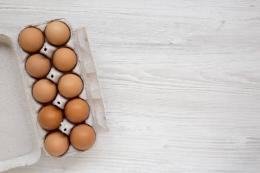 Kağıt bir kutuda çiğ kahverengi yumurta, üst manzara. Dümdüz, tepeden, yukarıdan. Boşluğu kopyala.