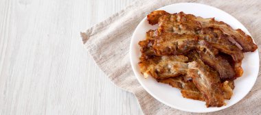 Beyaz ahşap bir masada beyaz bir tabakta ev yapımı domuz pastırması. Düşük açılı. Boşluğu kopyala.