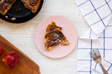 Beyaz ahşap arka planda pembe bir tabakta ev yapımı elmalı gözleme. Yukarıdan, dümdüz uzanmış.