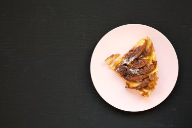Ev yapımı Apple Dutch Pannekoek Pancake 'i siyah bir yüzey üzerinde pembe bir tabakta, üst manzara. Dümdüz, tepeden, yukarıdan. Boşluğu kopyala.