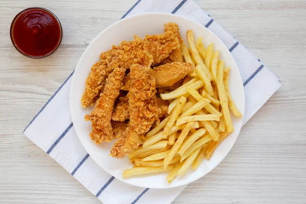 Homemade Crispy Chicken Tenders and French Fries on a white wooden background, top view. Flat  lay, overhead, from above.