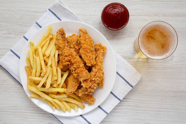 Домашний хрустящий цыпленок и картофель фри с соусом и стаканом холодного пива, вид сверху. Вид сверху, плоский лежал.